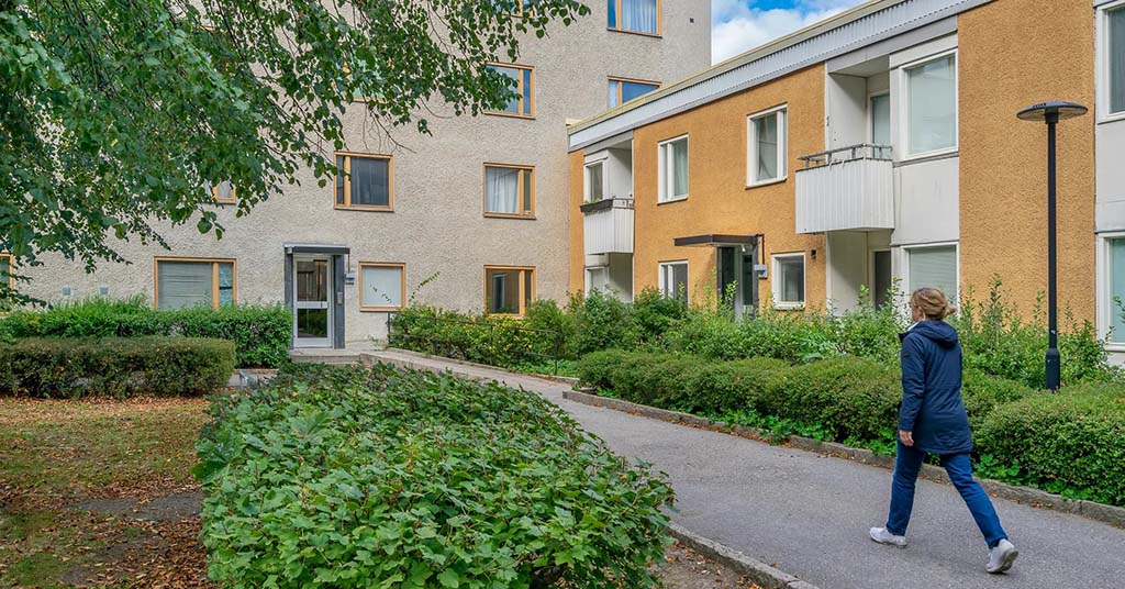 Gårdsbild på bostadshus med en person som promenerar.