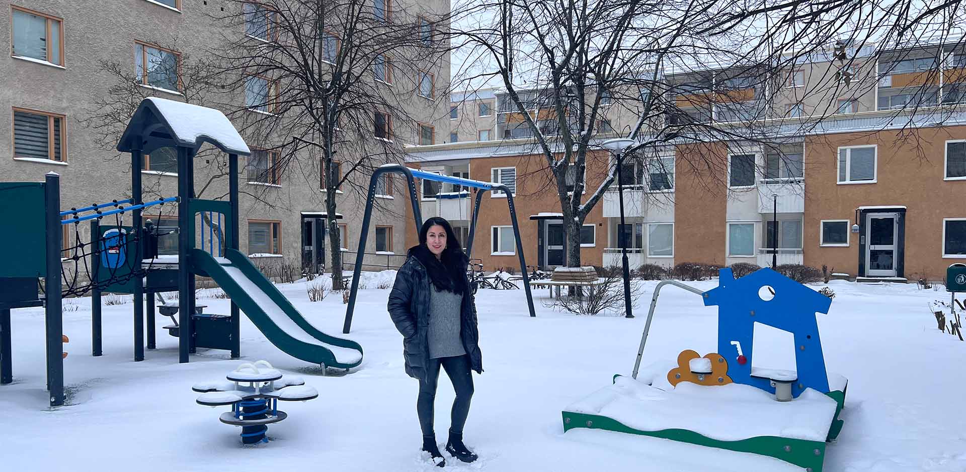 kvinna står framför en lekplats på vintern