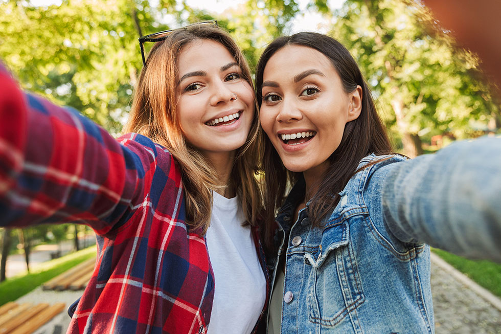 Två studenter som tar foto på sig själva utomhus