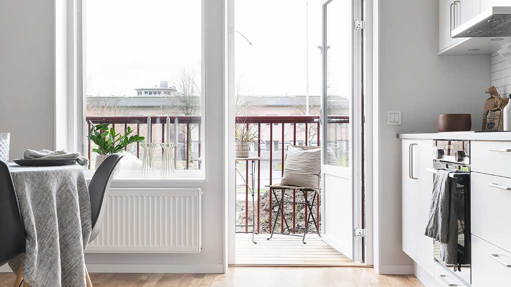 En dörr öppnas mot en balkong via köket i en ledig lägenhet.