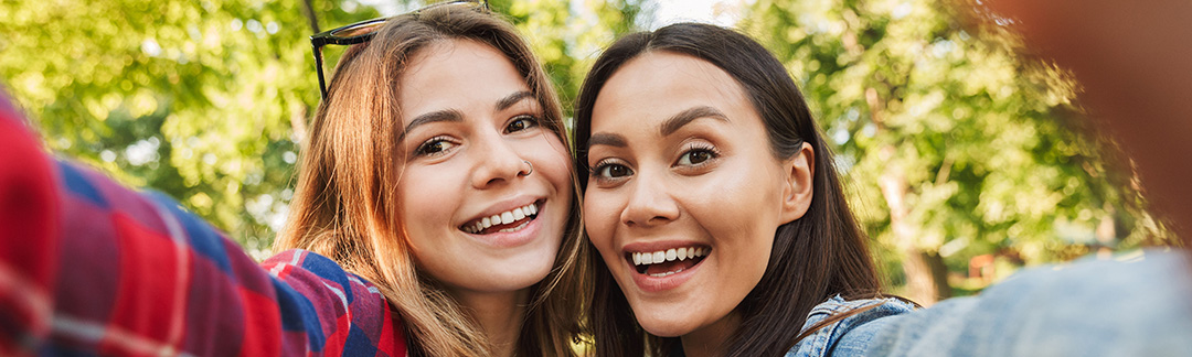 Två studenter som tar foto på sig själva utomhus